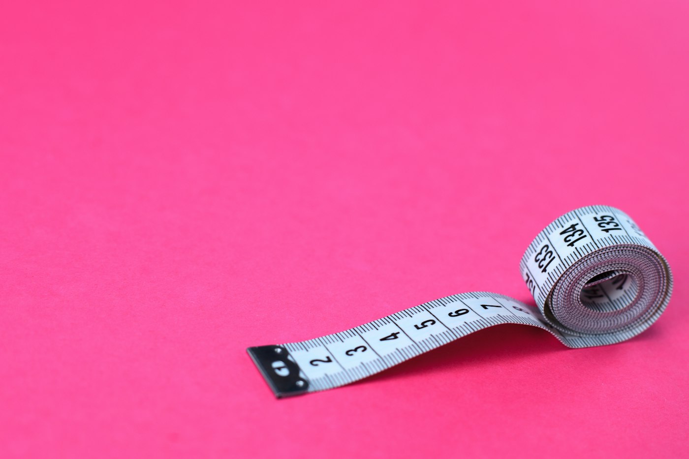 Photograph: measuring tape on a pink background